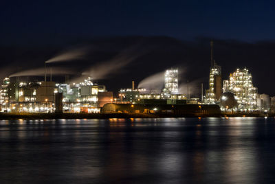 Illuminated harbor by sea against sky at night