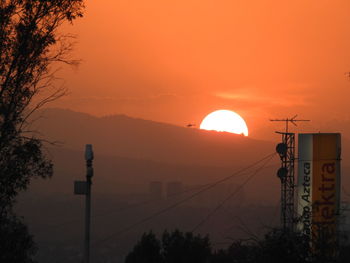 Silhouette electricity pylon against sky during sunset