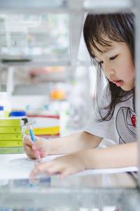 Close-up of girl drawing in paper at home