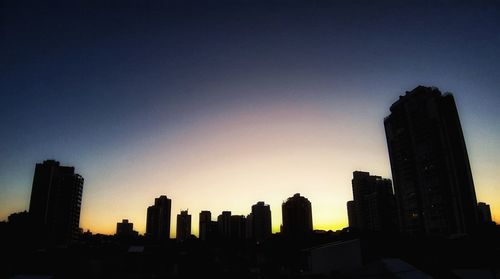 Silhouette buildings against sky at dusk