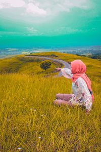 Rear view of woman on grassy field against sky