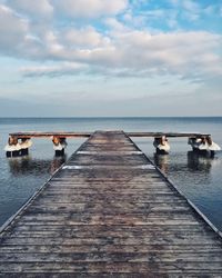 Pier on sea against cloudy sky