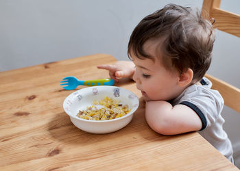 Little boy is eating eggs for breakfast and fooling around making faces