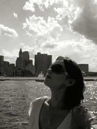 Young woman wearing sunglasses against sky in city