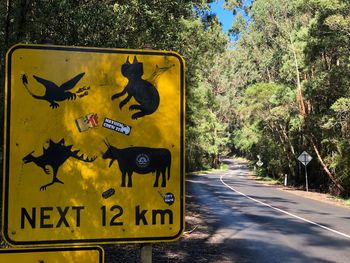 Text on road sign against trees