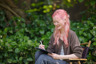 Young woman using mobile phone while sitting outdoors