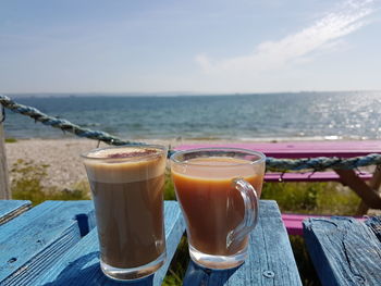 Close-up of coffee on table by sea against sky