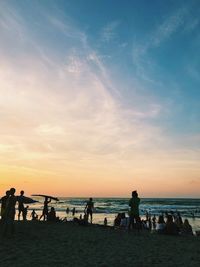 Silhouette people on beach against sky during sunset