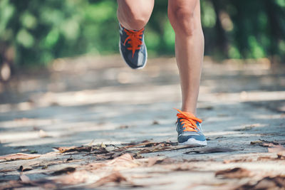 Low section of young woman jogging on road