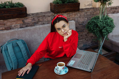 Woman using mobile phone while sitting on table