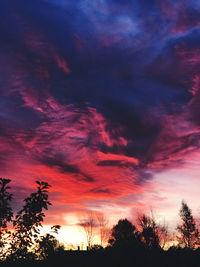 Low angle view of silhouette trees against dramatic sky