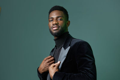 Portrait of young man standing against black background