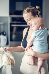 Side view of mother carrying daughter at home