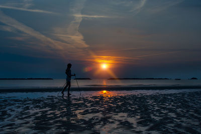 Silhouette person standing on beach against sky during sunset