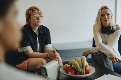 Blond girl sitting by non-binary person during counseling at high school