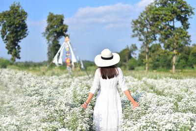 Rear view of woman standing on field against sky