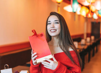 Beautiful young asian woman in red clothes with red gift bag celebrating chinese new year