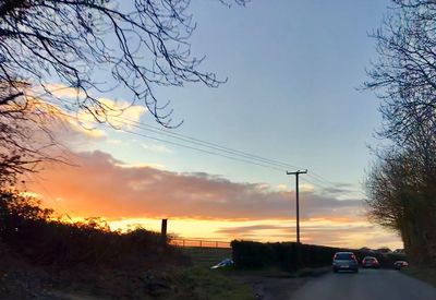 Cars on road against sky during sunset