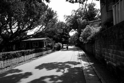 Road amidst trees in city against sky