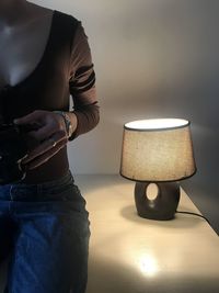 Midsection of man holding illuminated electric lamp