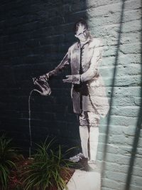 Full length of young woman standing against wall