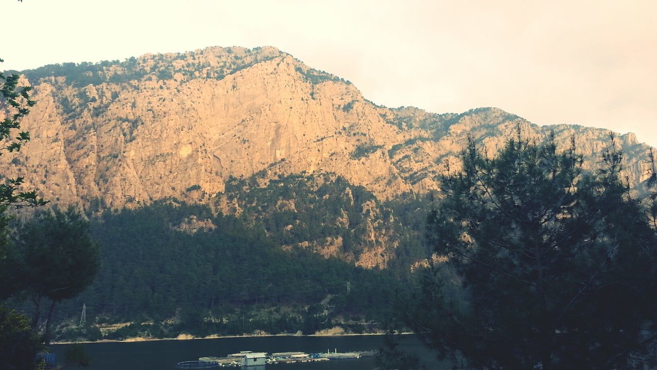 mountain, tranquil scene, scenics, tree, tranquility, clear sky, beauty in nature, mountain range, nature, water, non-urban scene, idyllic, copy space, landscape, sky, rock formation, rock - object, outdoors, no people