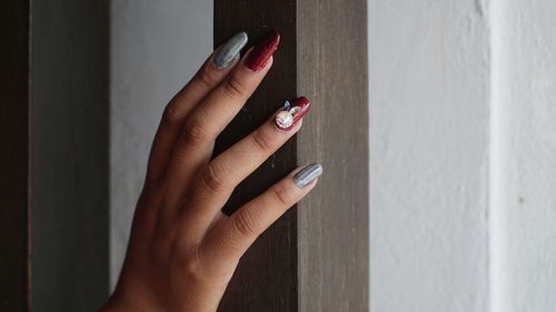 Close-up of woman hand with nail art on wall