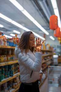 Young woman holding illuminated string light in supermarket