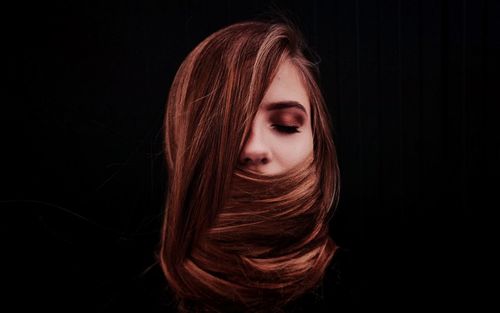 Close-up of young woman over black background