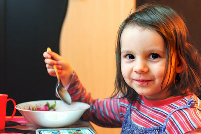 Portrait of cute girl eating food on table