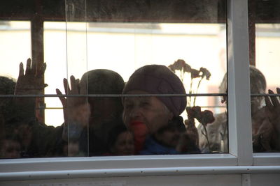 Close-up of people looking through window