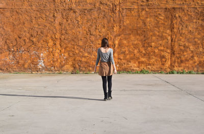 Rear view of woman walking towards wall