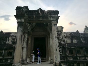 People standing at old historic building against sky