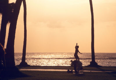 Silhouette of statue at beach during sunset