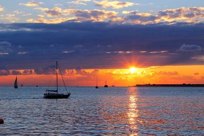 Silhouette sailboats in sea against sky during sunset