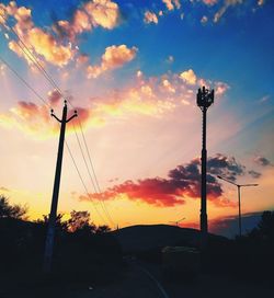 Low angle view of silhouette telephone pole against sky during sunset