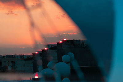 Illuminated city against sky at sunset
