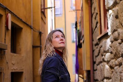 Portrait of woman standing against wall of building