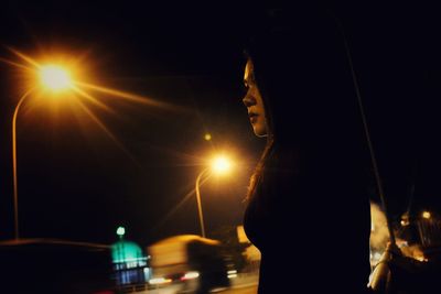 Woman standing in illuminated city against sky at night