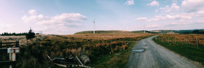 Panoramic view of road amidst field against sky