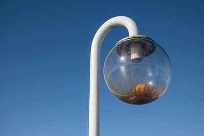 Low angle view of abandoned street light against clear blue sky