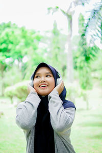 Portrait of young woman standing against trees