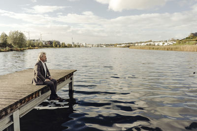 Senior man sitting on jetty at a lake