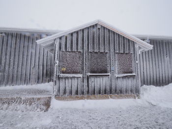 House on snow covered field against sky