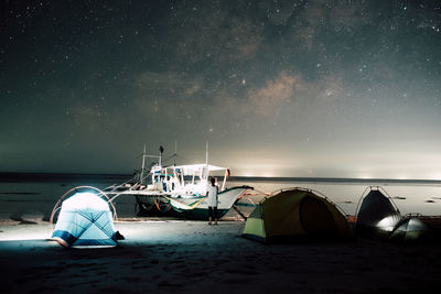 Rear view of mid adult woman standing at beach against star field