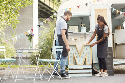 Owners placing letter m outside food truck on street