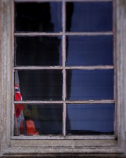 Rear view of man sitting on window of building