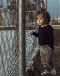 Cute girl standing by chainlink fence