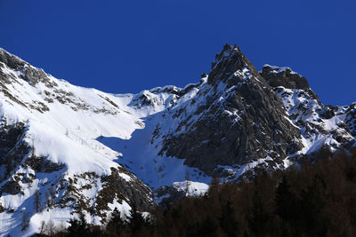 Scenic view of snow covered mountains against clear blue sky