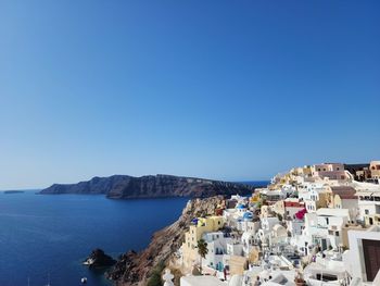 Townscape by sea against clear blue sky